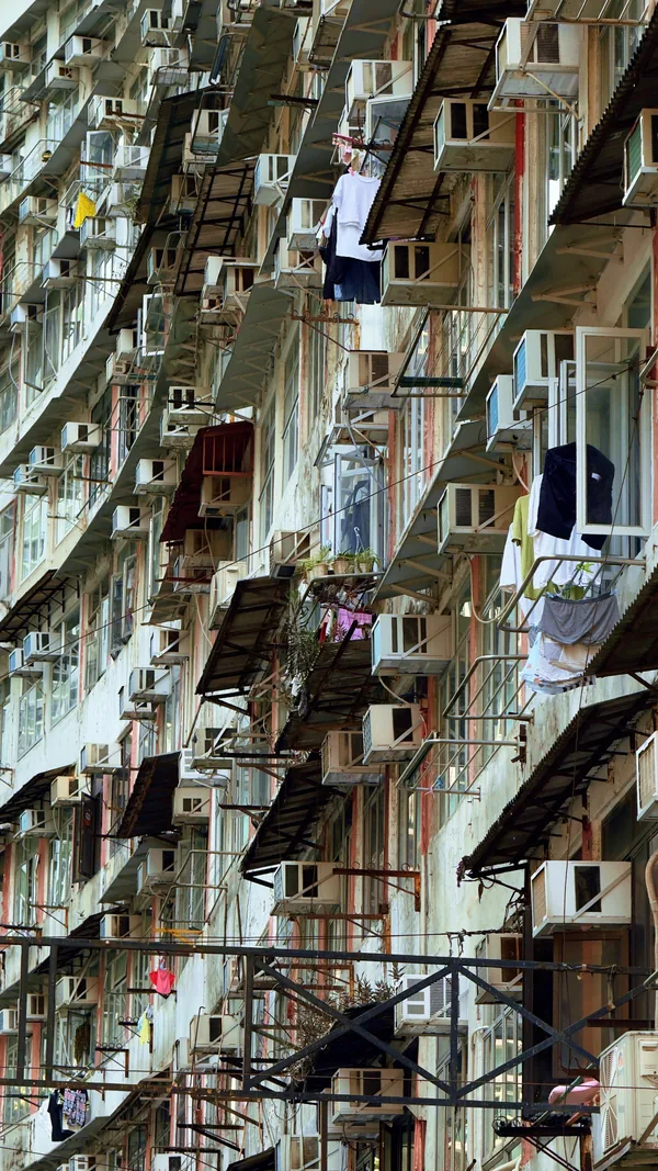 Tall weathered apartment building with balconies and air conditioners